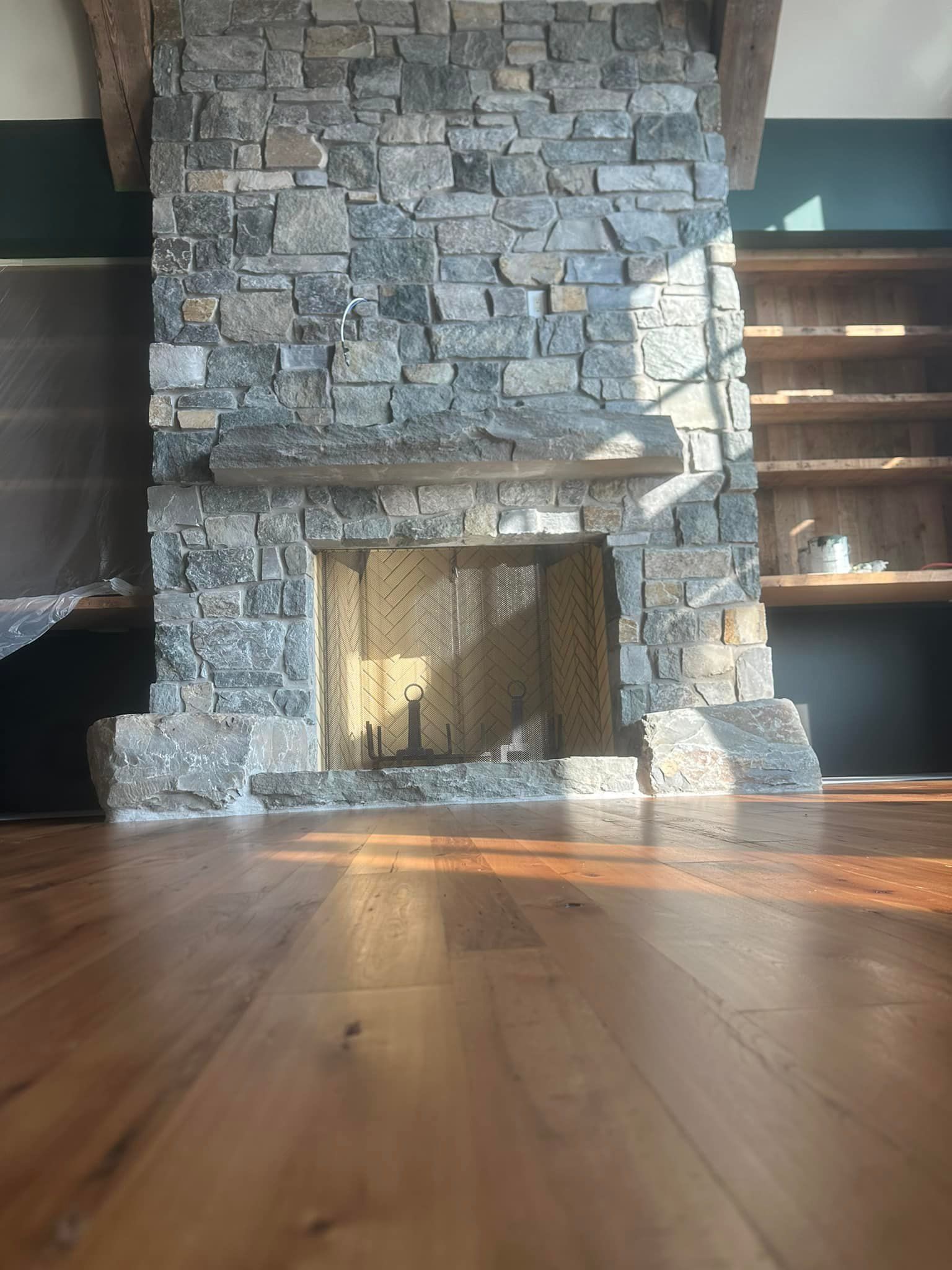 A stone fireplace with a wooden floor in a living room.