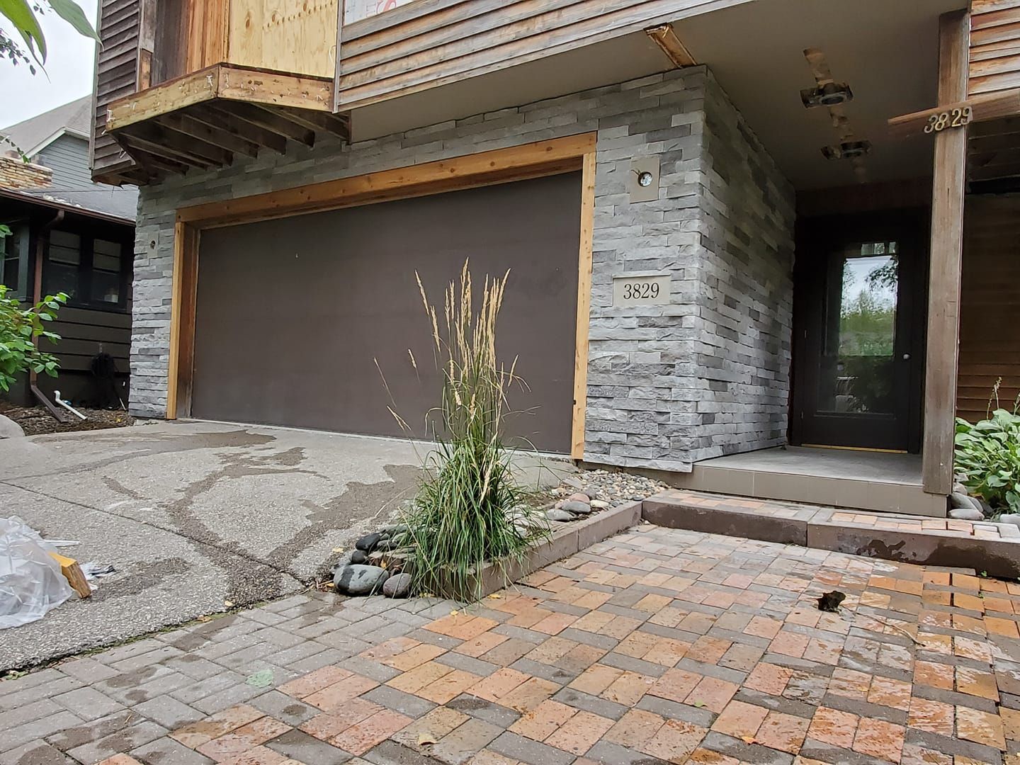 A house with a garage door and a brick driveway.