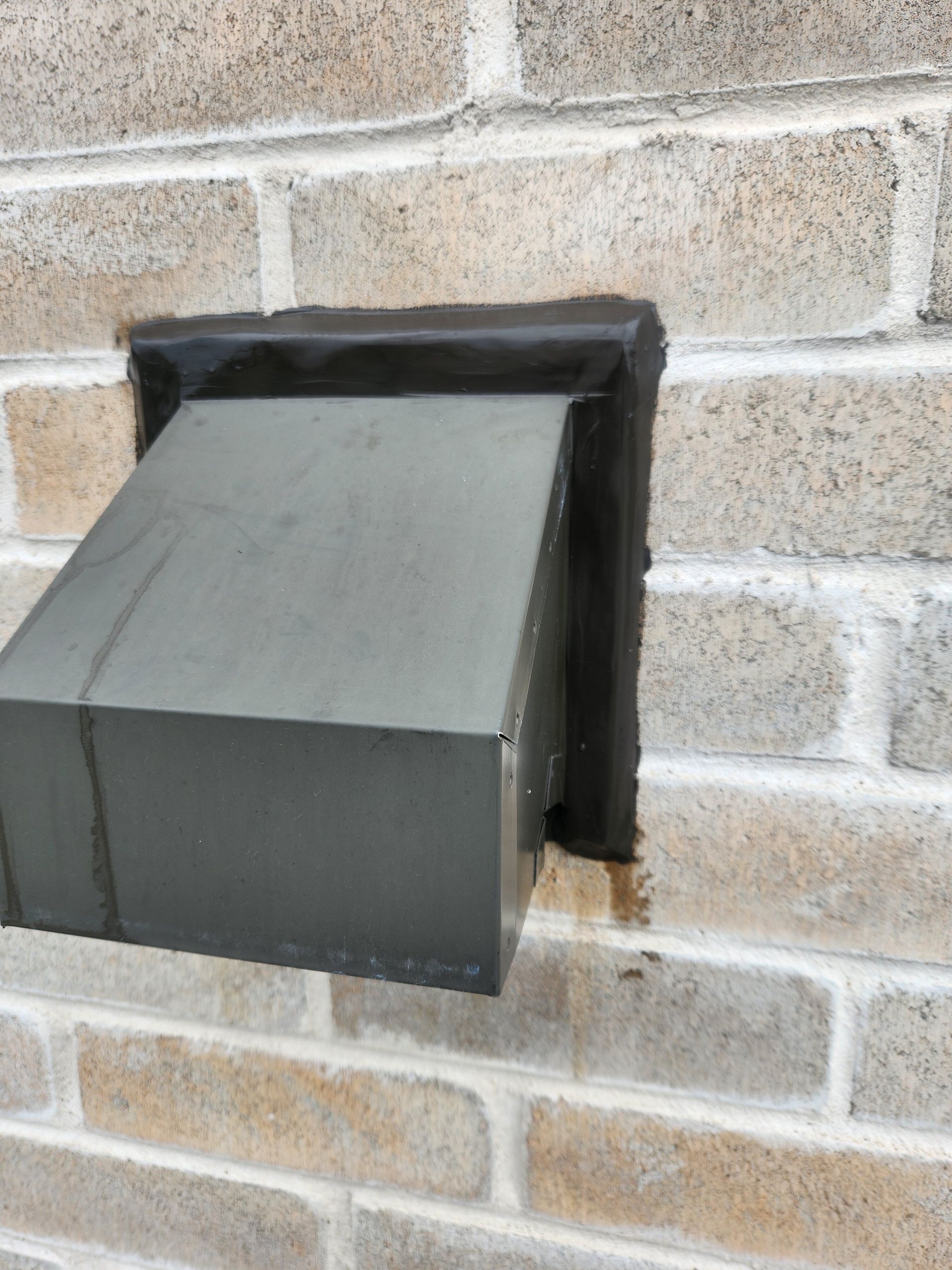 Une boîte en métal est posée sur un mur de briques.