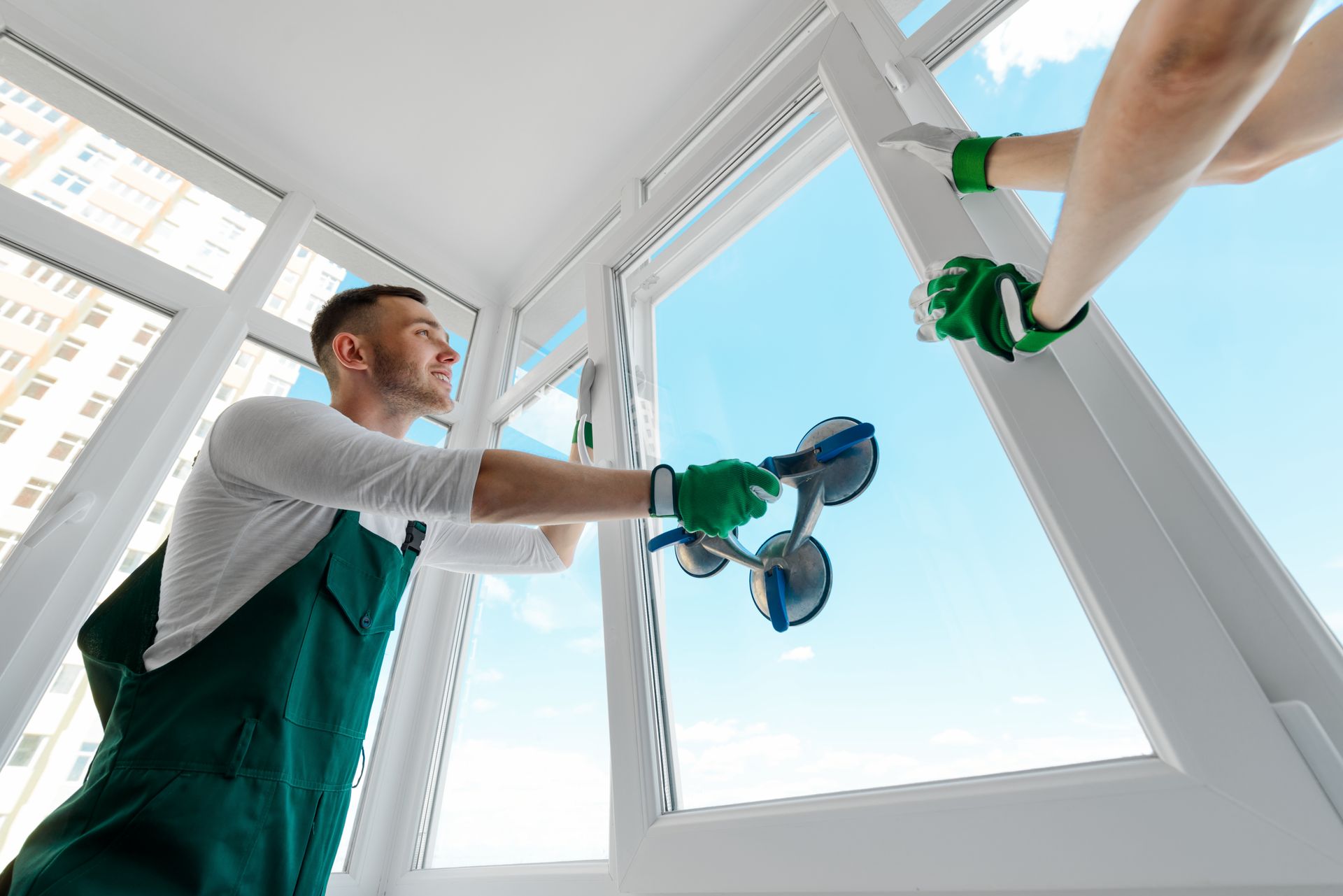 Un homme installe une fenêtre sur un balcon.