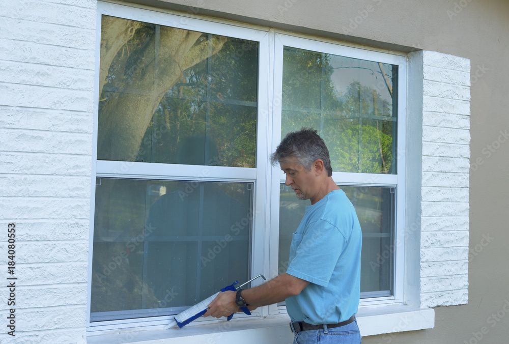 Un homme installe une fenêtre dans une maison.