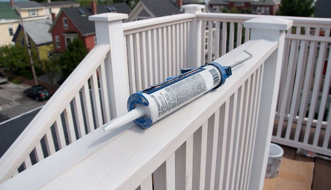 Une boîte de mastic est posée sur une balustrade blanche.