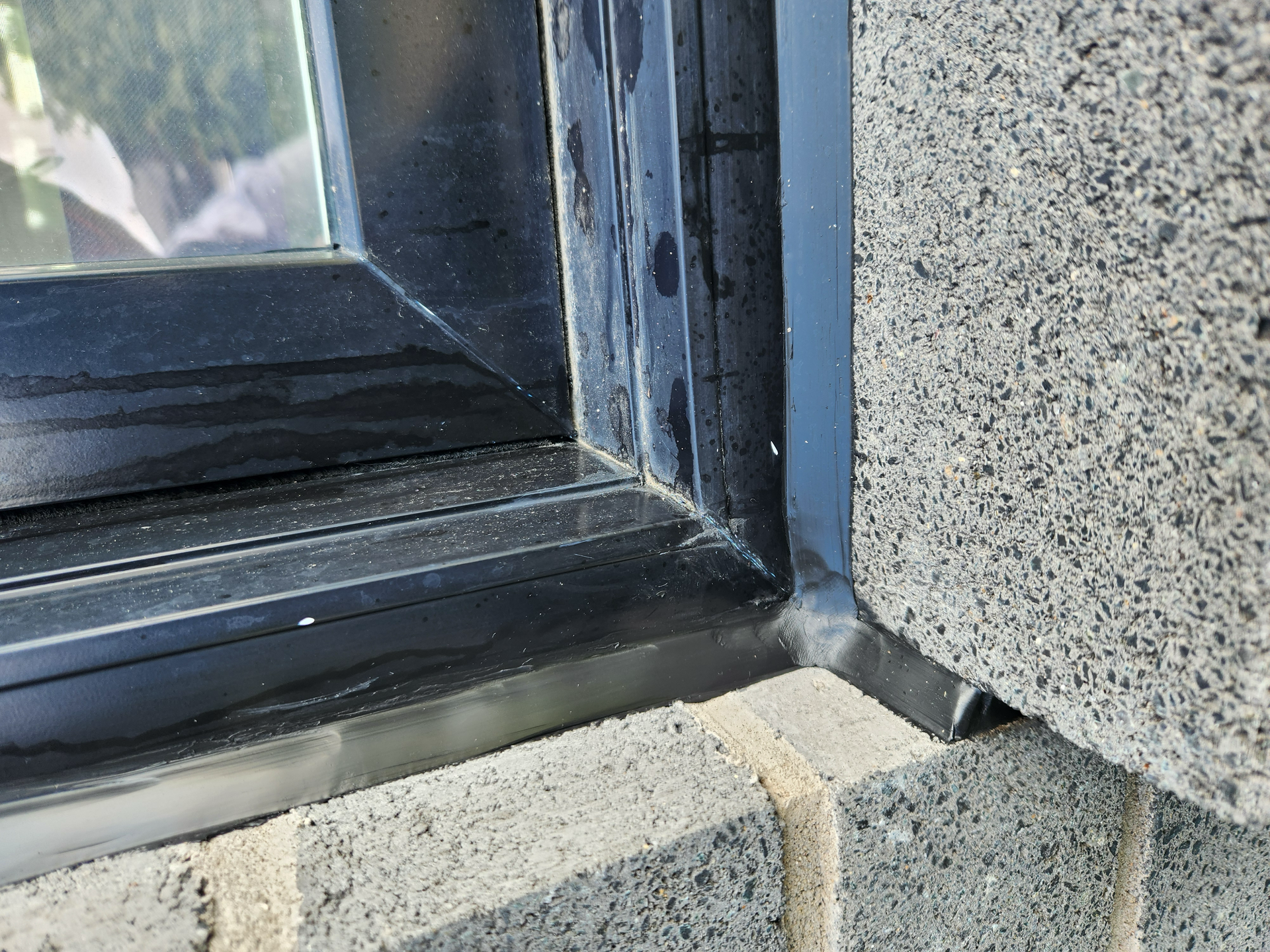 Cadre de fenêtre noir sur fond de briques grises.