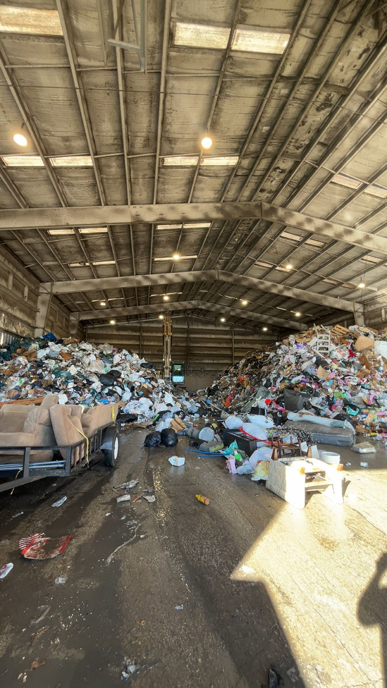 Indoor view of a landfill; heaps of trash surround a wheeled vehicle.