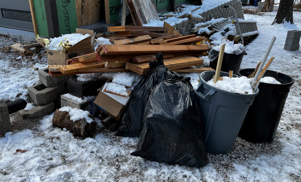 Interior with debris and trash; doorway to a deck. Brown wood pieces, black trash bags.