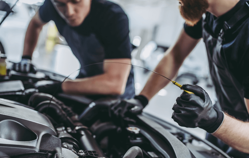 two mechanics performing service on a car