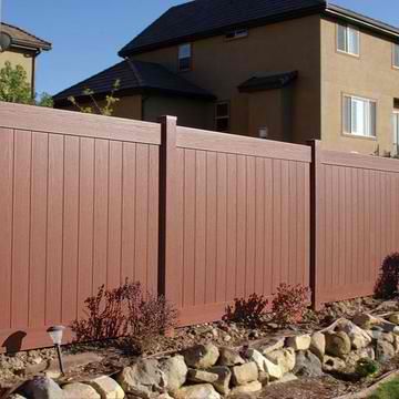 A wooden fence surrounds a rock garden in front of a house.