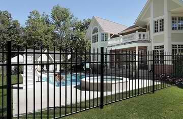 A large house with a pool behind a metal fence.