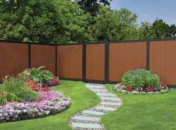 A wooden fence surrounds a garden with flowers and a walkway.