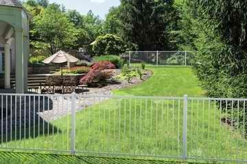 A white fence surrounds a lush green backyard.
