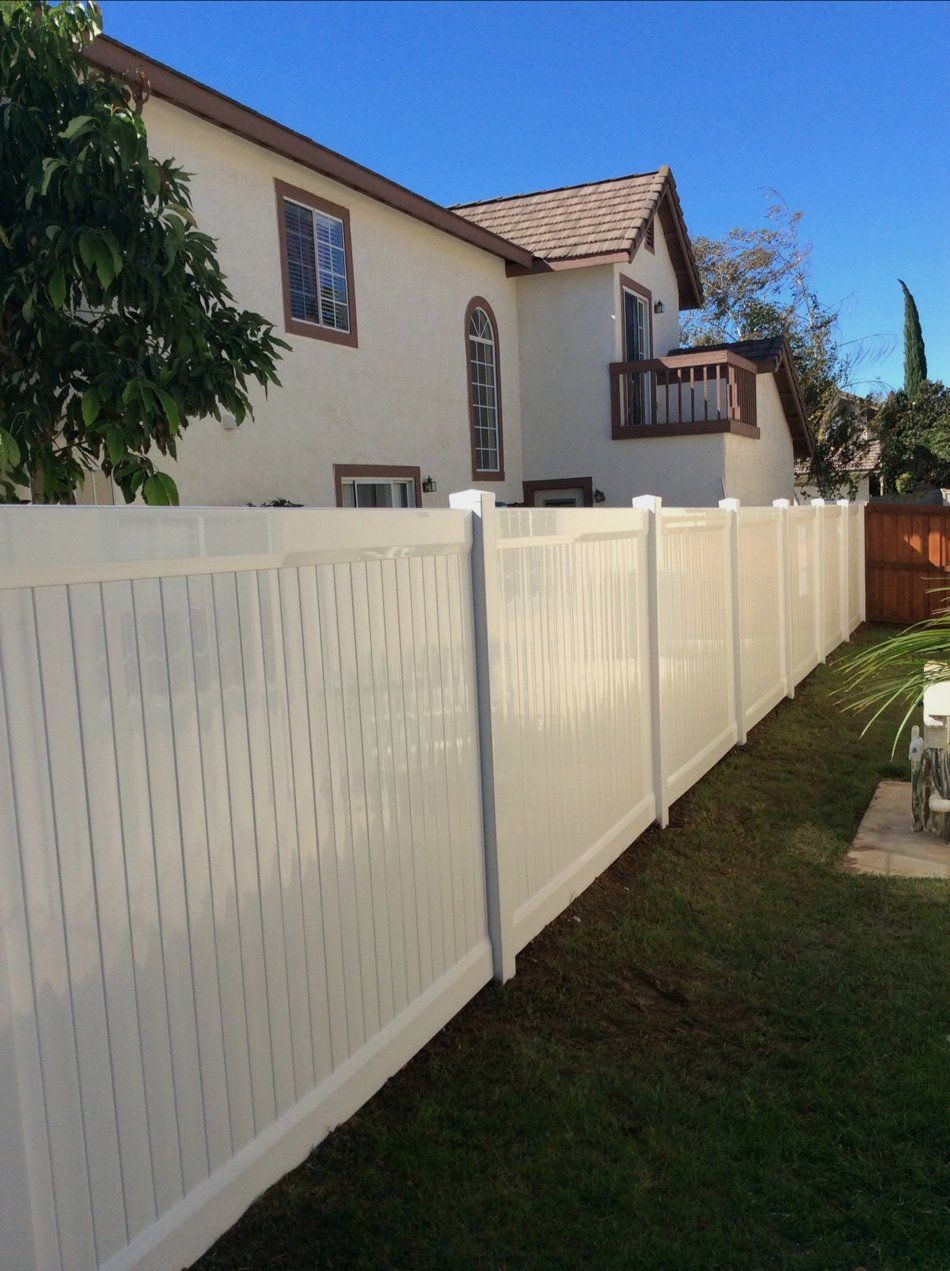 A white fence is in front of a house