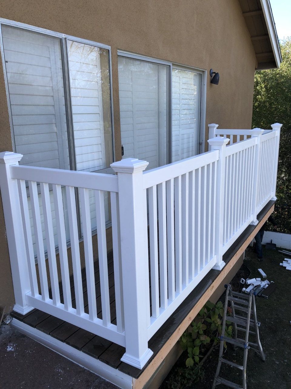 A white railing is being installed on a balcony