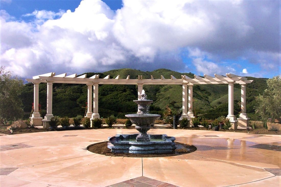 A fountain with a pergola in the background