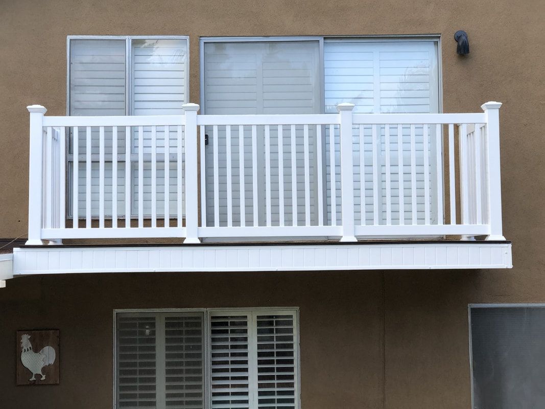 A balcony with a white railing on the side of a building