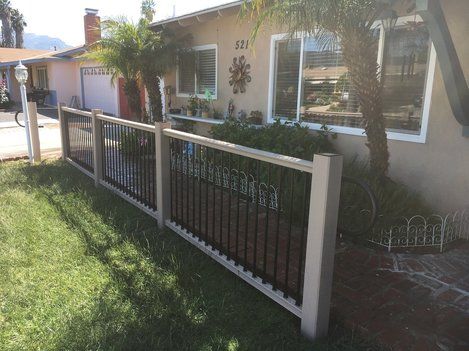 A house with a fence around it and a lawn in front of it.