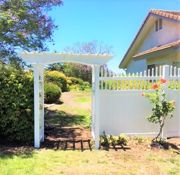 A white fence with a pergola in front of a house