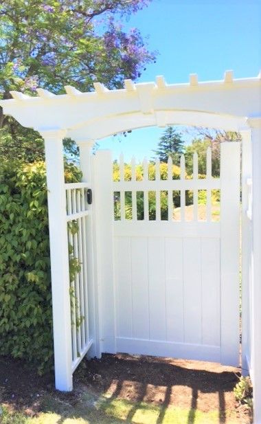 A white fence with a gate in the middle of it.