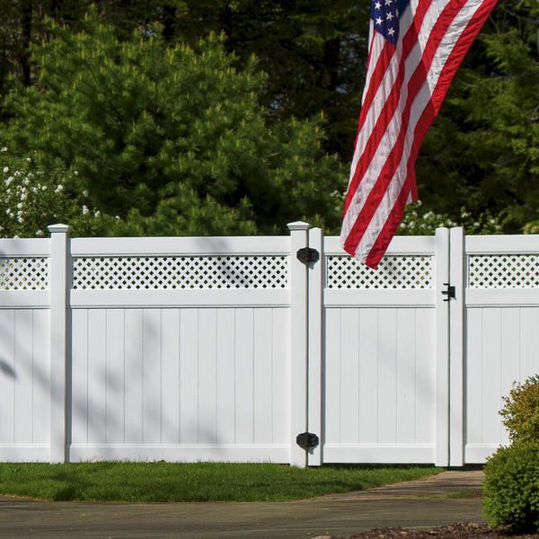 An american flag is flying in front of a white fence