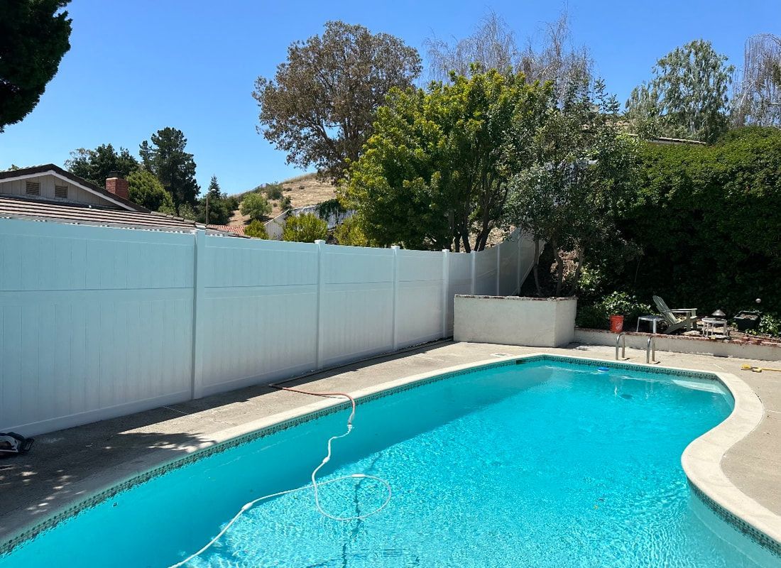 A large swimming pool with a white fence surrounding it