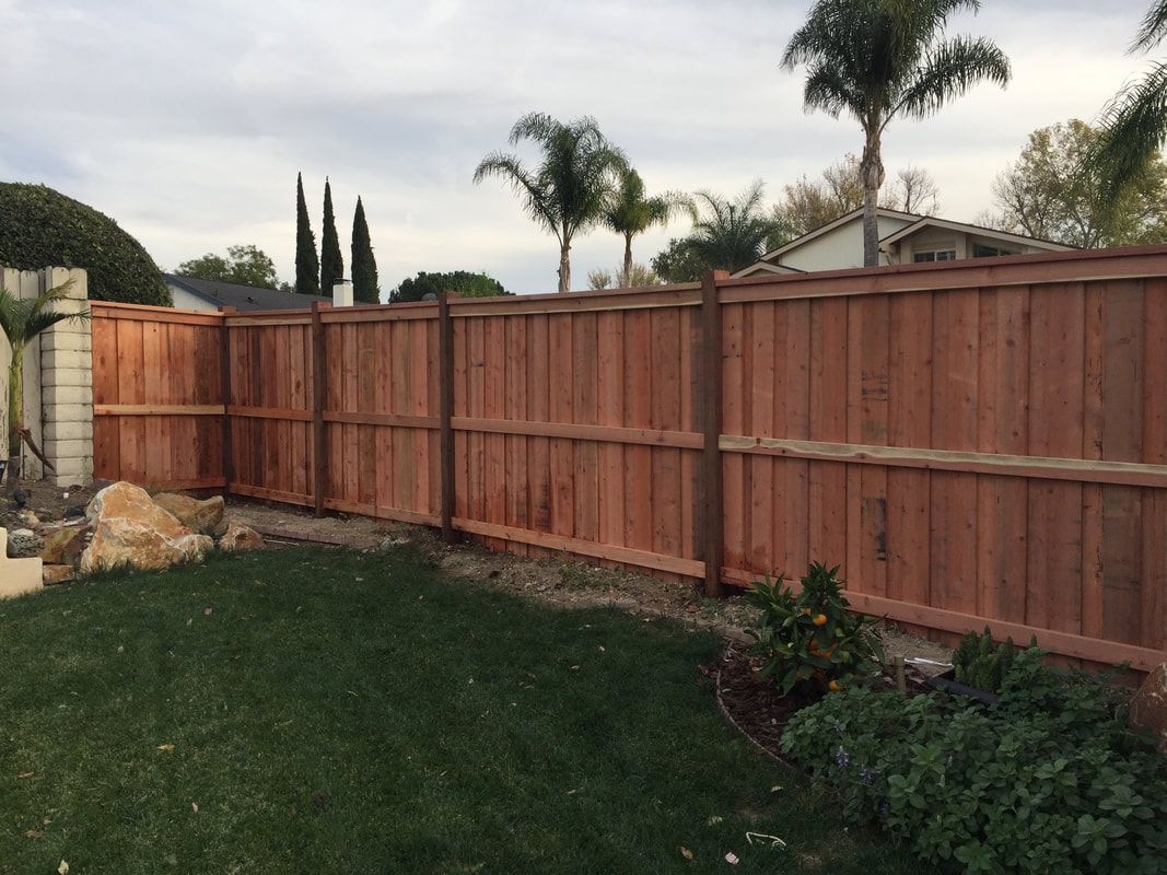 A wooden fence is in the backyard of a house.