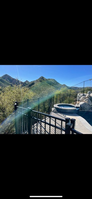A view of a swimming pool and mountains from a balcony.