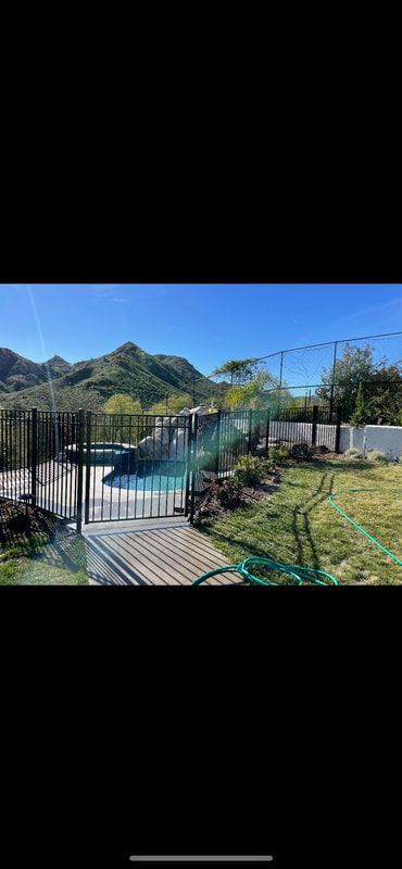 A fence around a swimming pool with mountains in the background.