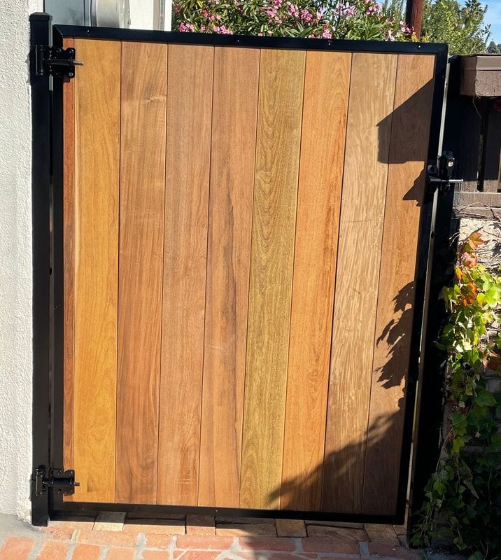 A wooden gate with a black frame is open