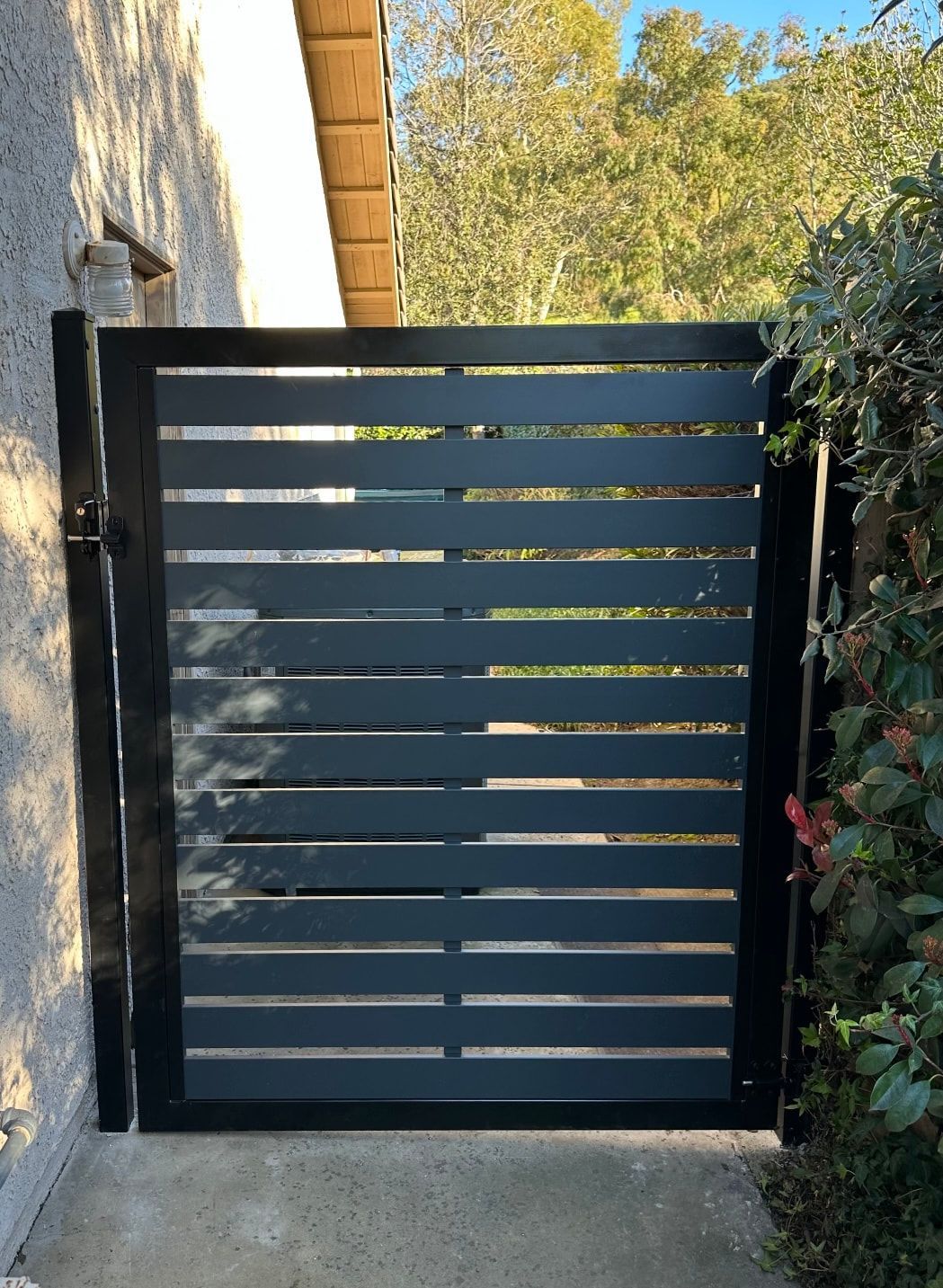 A black gate is sitting on a sidewalk next to a house.