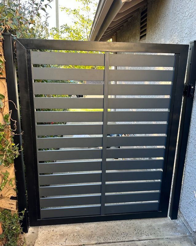 A black gate with a wooden fence in front of a house.