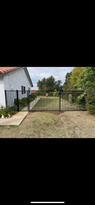 A black gate is sitting in front of a white house.