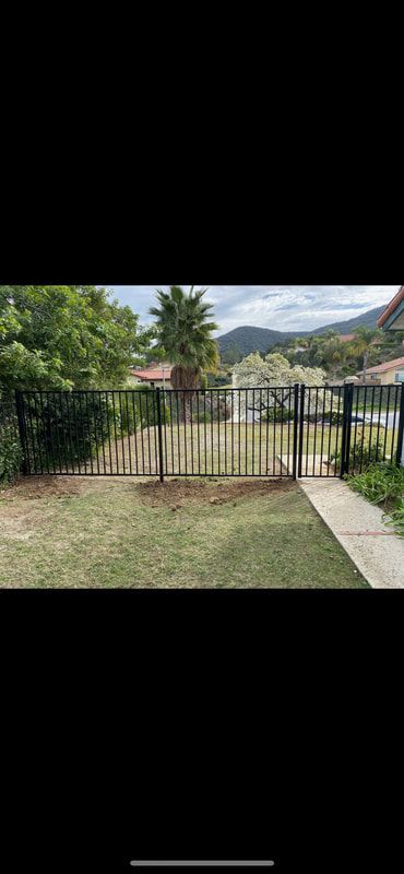 A black metal gate is sitting in the middle of a lush green yard.