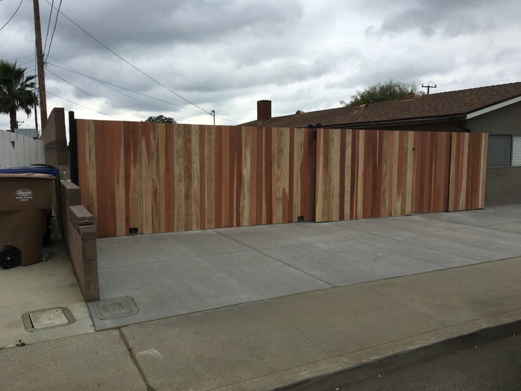 A wooden fence surrounds a driveway in front of a house