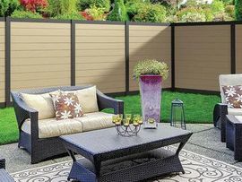A patio with a couch , chairs , coffee table and a fence.