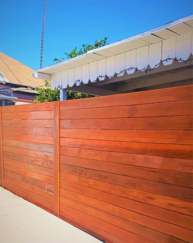 A wooden fence is surrounding a house on a sunny day.