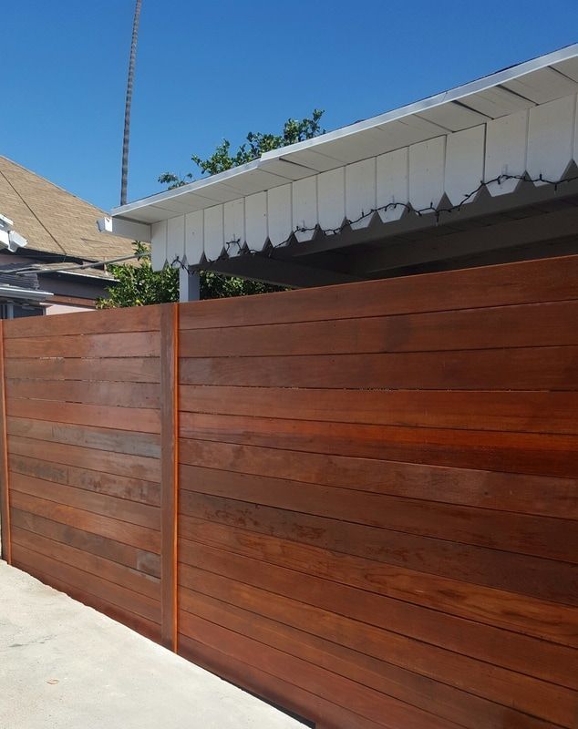 A wooden fence surrounds a house on a sunny day