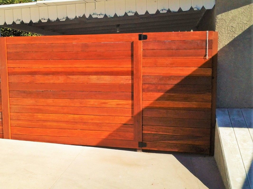 A wooden gate with a shadow on the ground