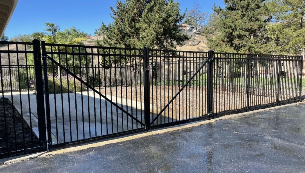 A black wrought iron fence is surrounding a driveway.