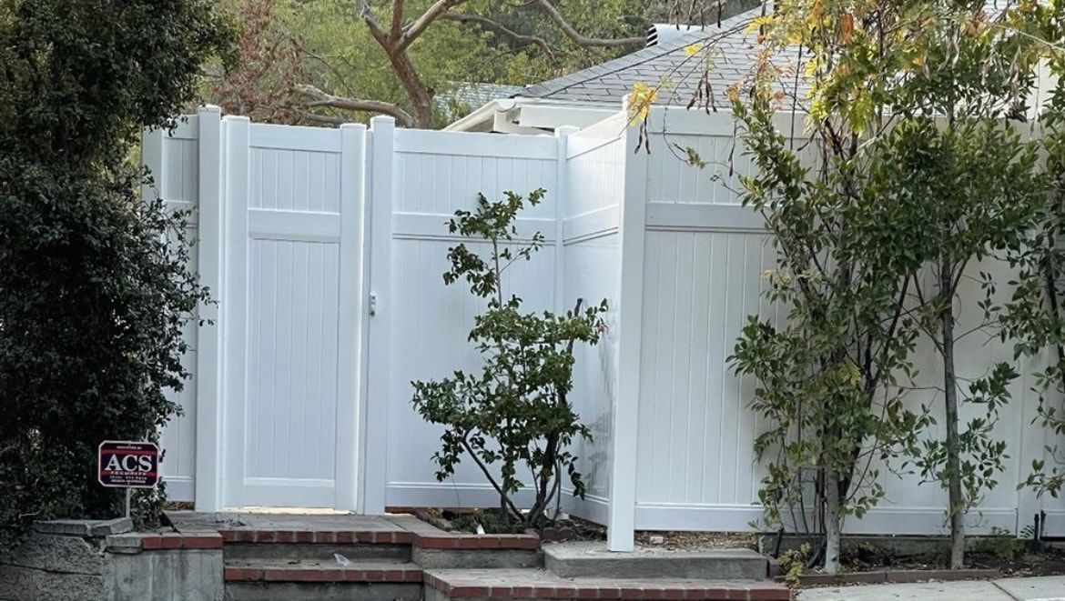 A white fence with a gate in front of a house.