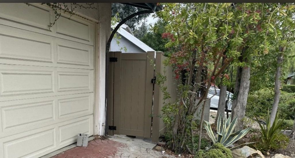 A white garage door is surrounded by trees and bushes.