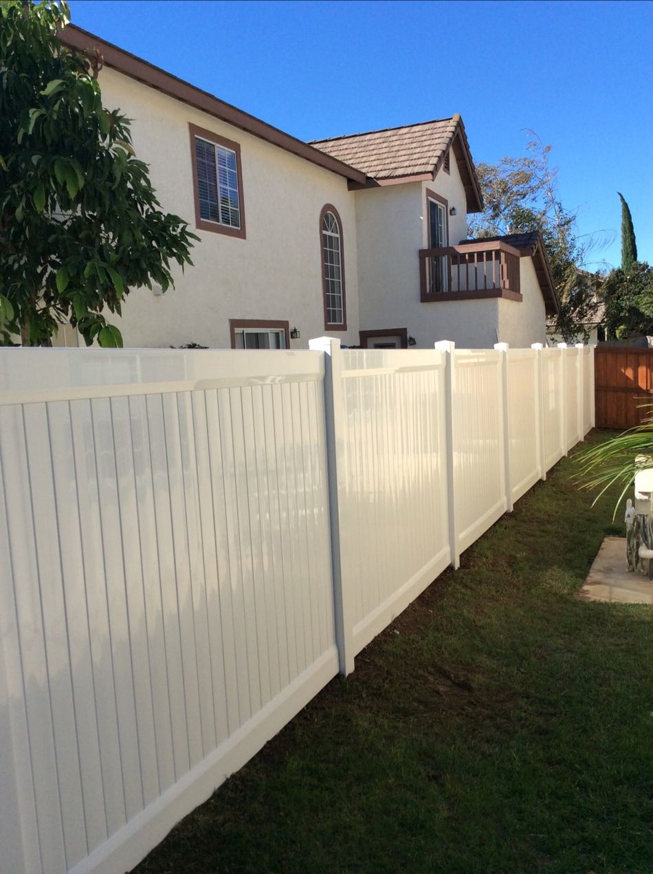 A white fence is in front of a house