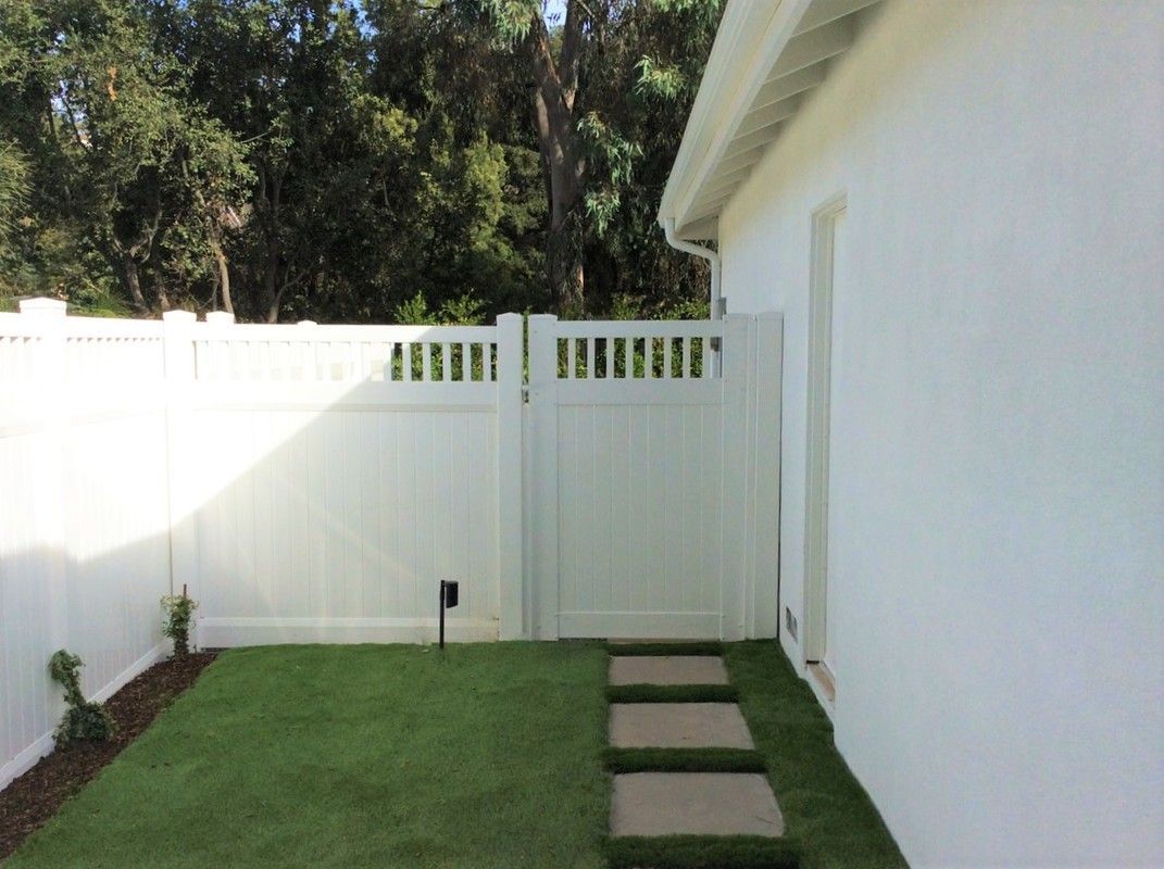 A white house with a white fence and a lawn in front of it