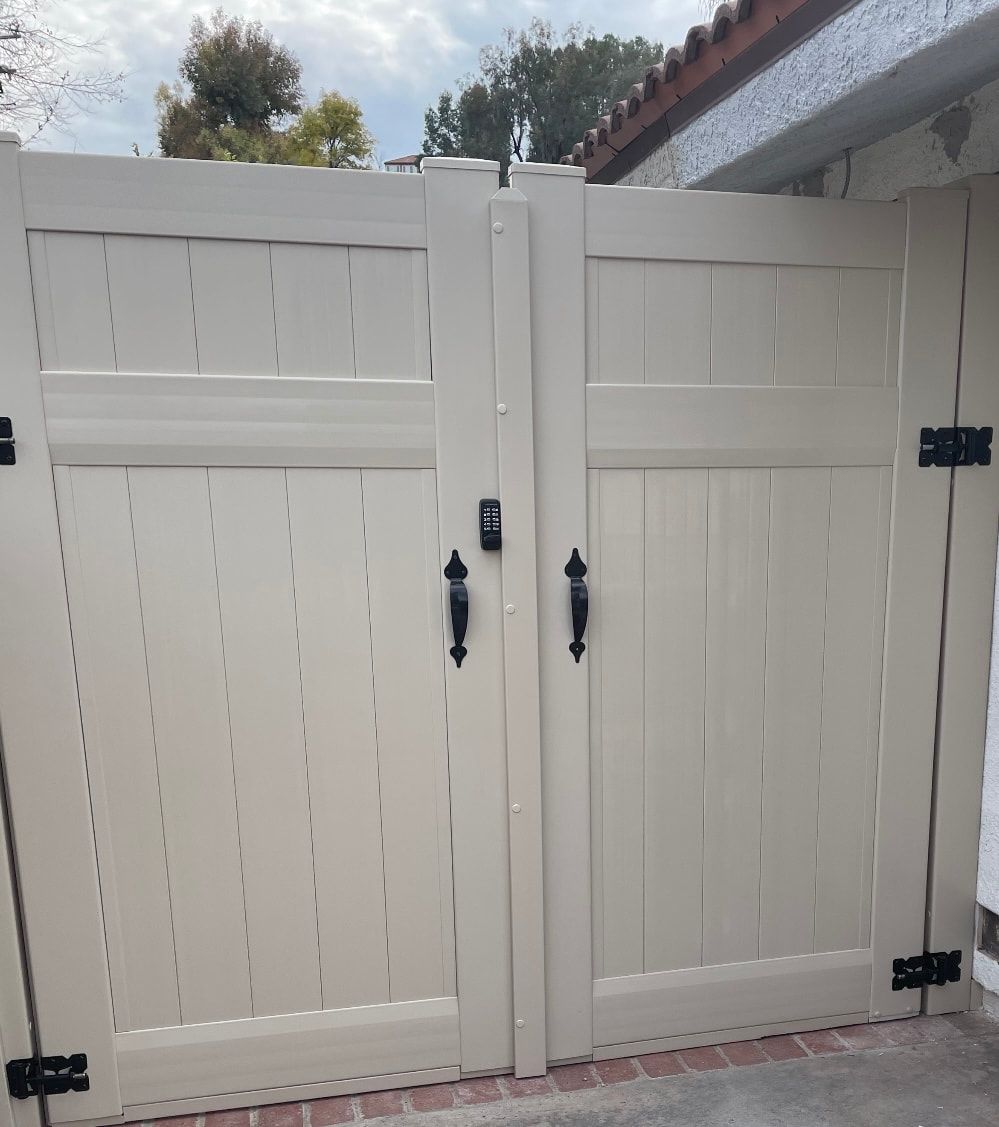 A white wooden gate with black handles is open