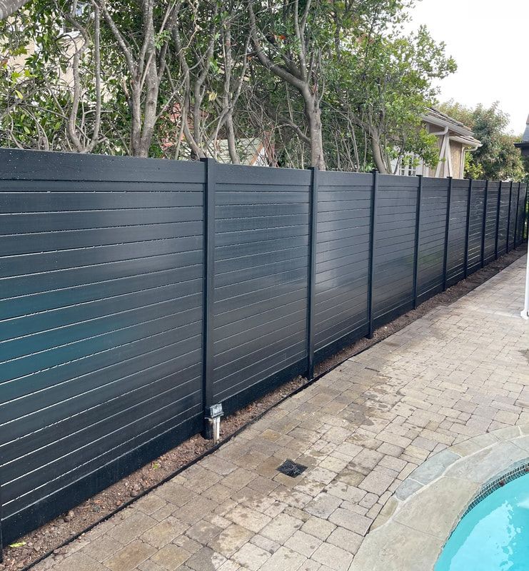 A black fence is sitting next to a pool.