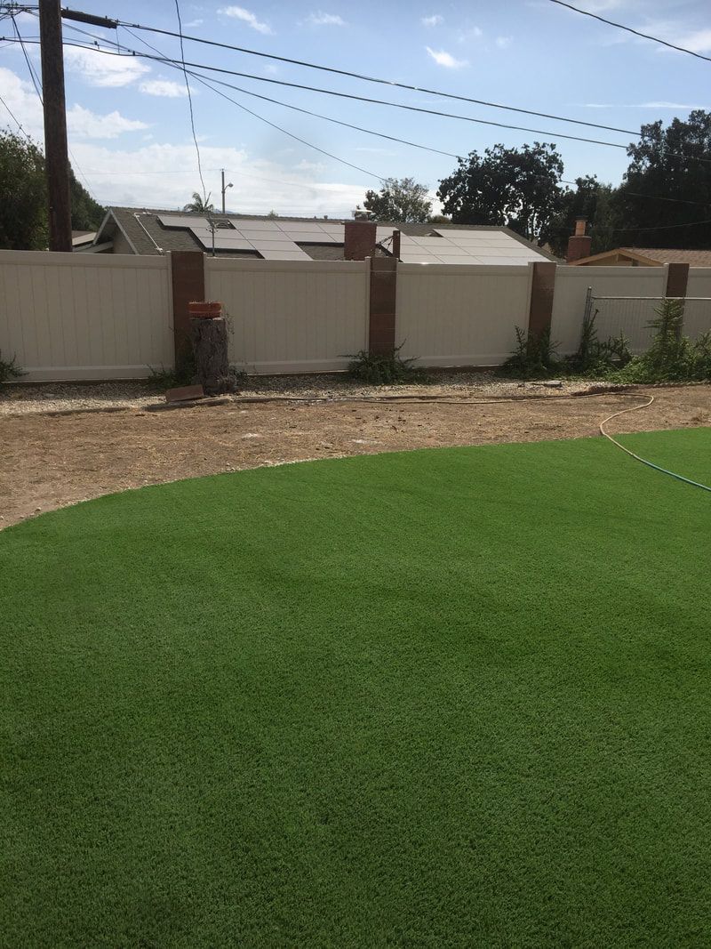 A backyard with a fence and a lush green lawn.