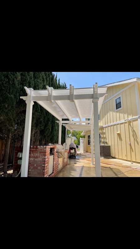 A white pergola is sitting in the backyard of a house.