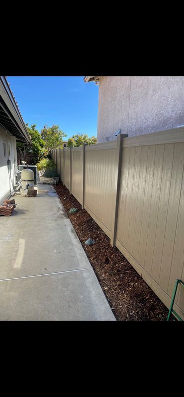 A fence along a sidewalk next to a house.