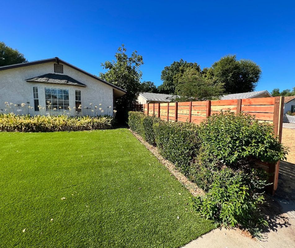 A house with a lush green lawn and a wooden fence
