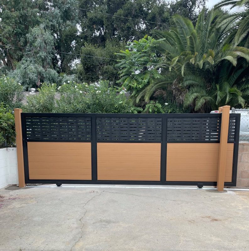 A wooden and black sliding gate with a palm tree in the background