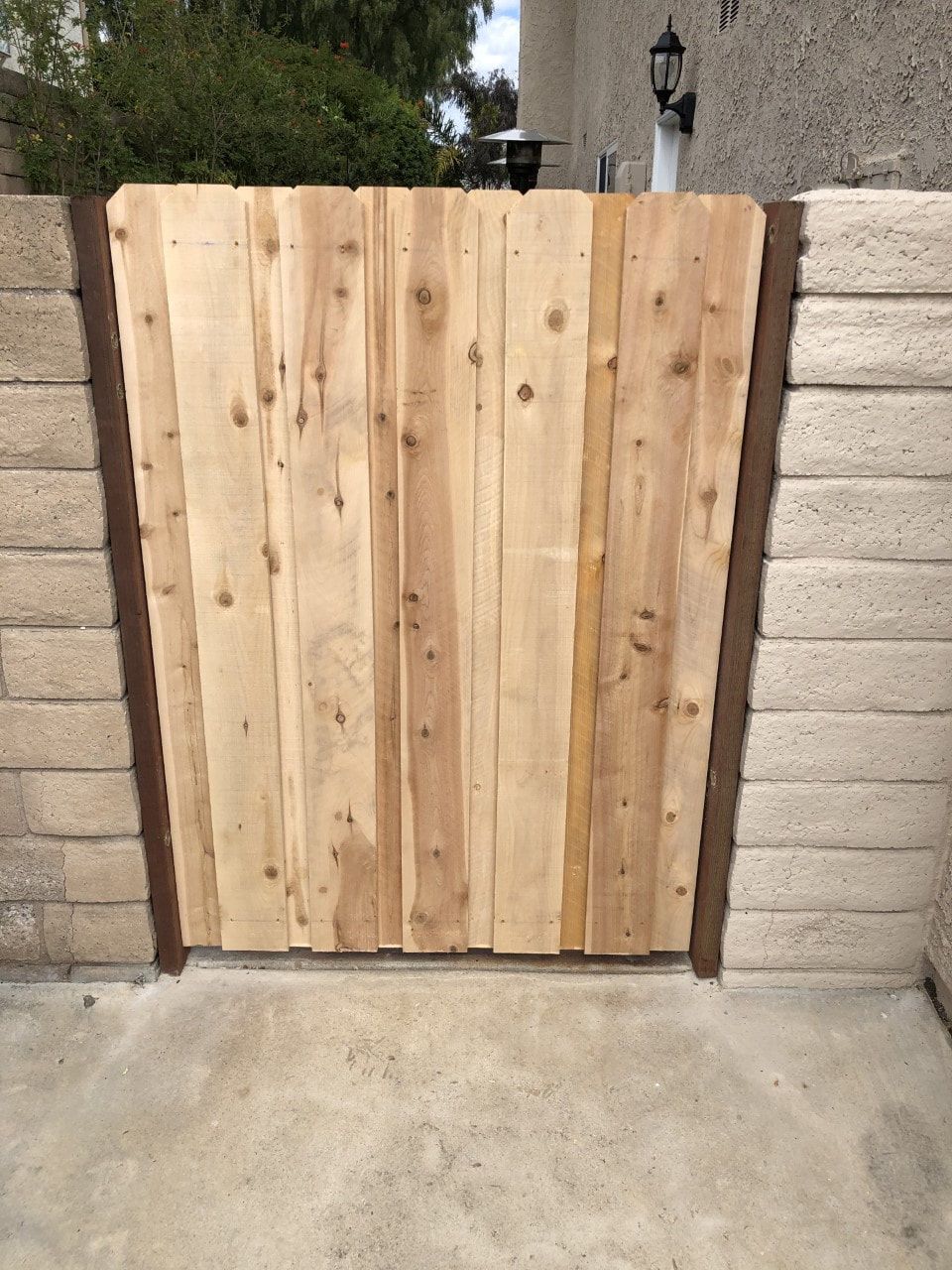 A wooden gate is sitting in front of a brick wall.