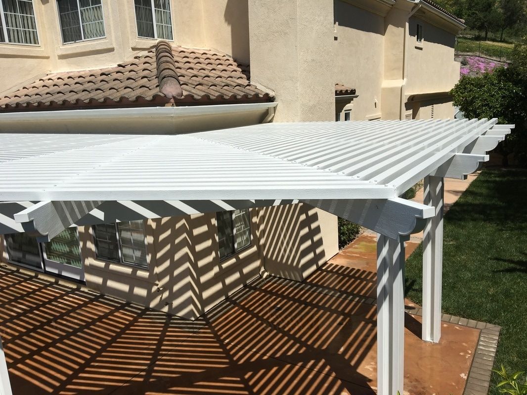 A white pergola is sitting in front of a house.